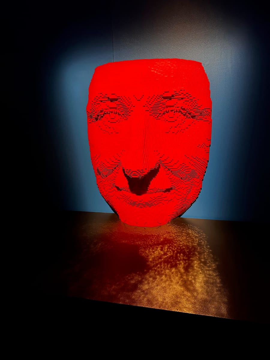 A red brick-built face glowing in a dark gallery