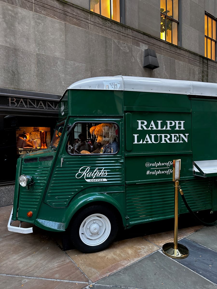 A vintage green coffee truck parked on a city sidewalk