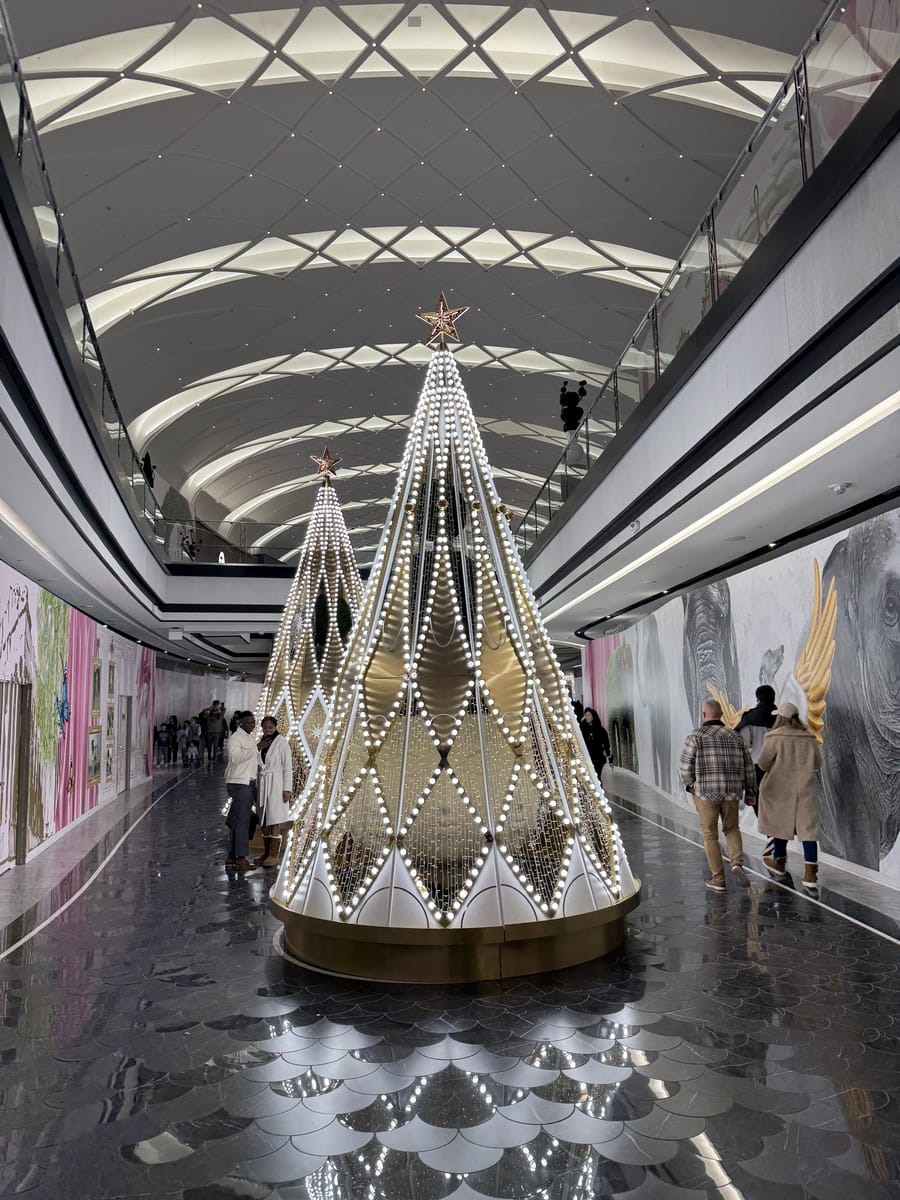 A lit sculptural tree under a vaulted glass ceiling