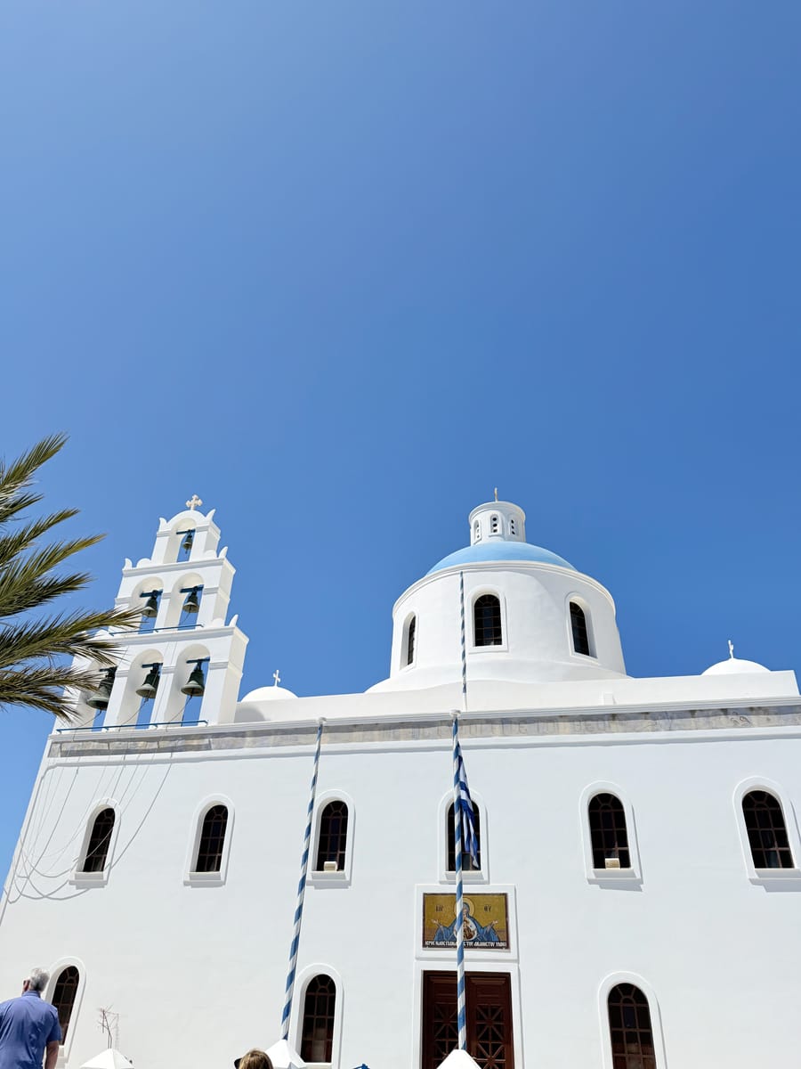 A white church with a bell tower and blue dome