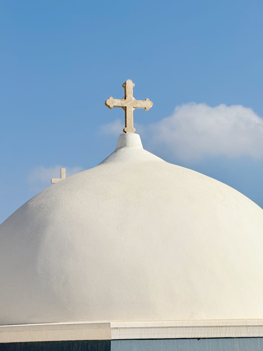 A white dome topped with a stone cross